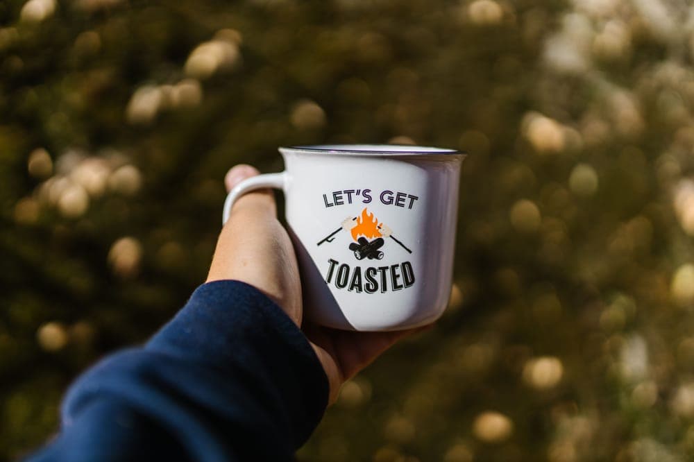 A hand holding an enamel camp mug