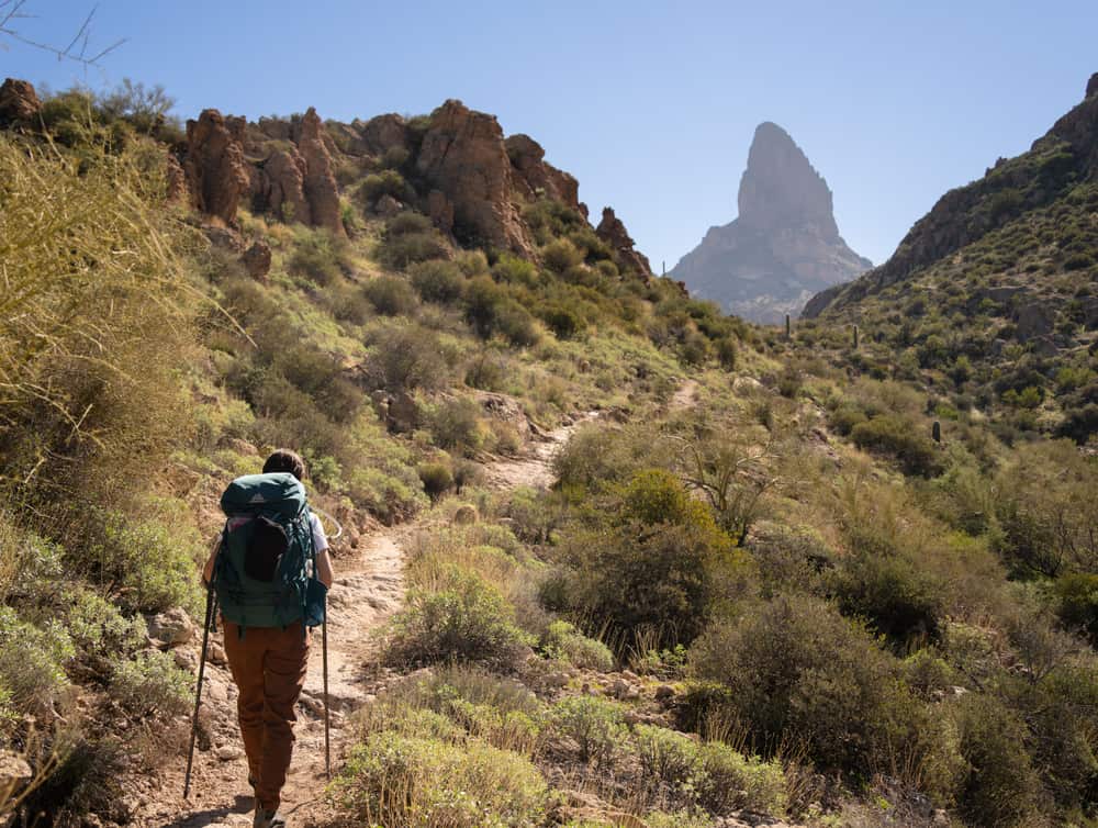 A hiker on a desert trail among rocky mountains