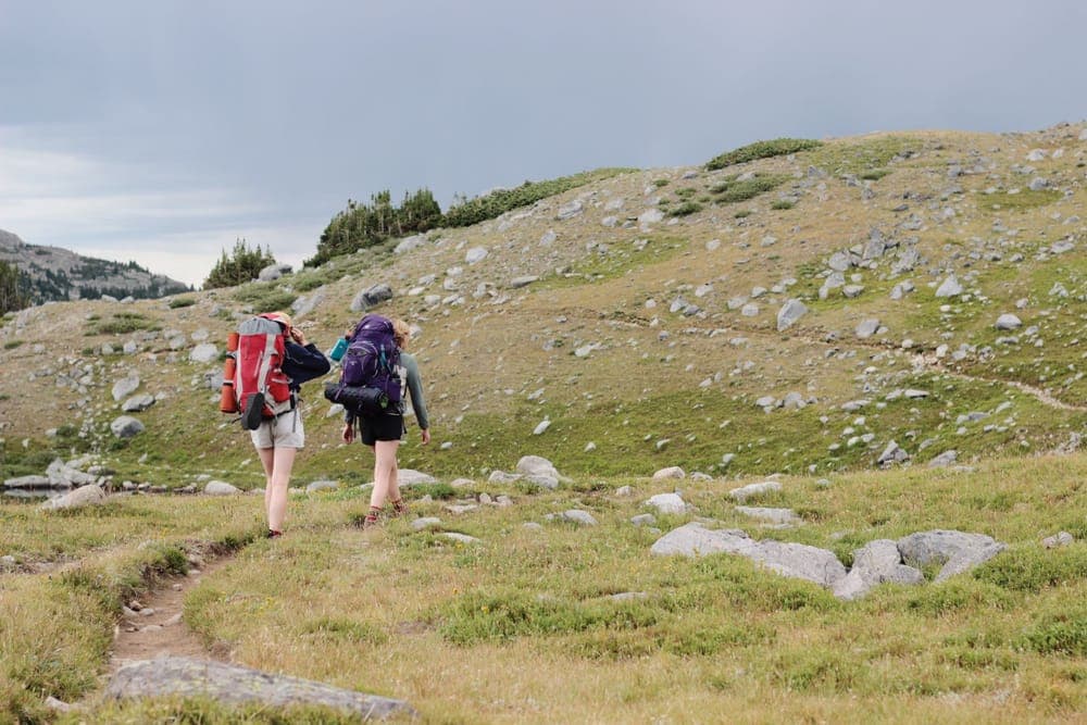 Two hikers with backpacks on a rocky mountain path
