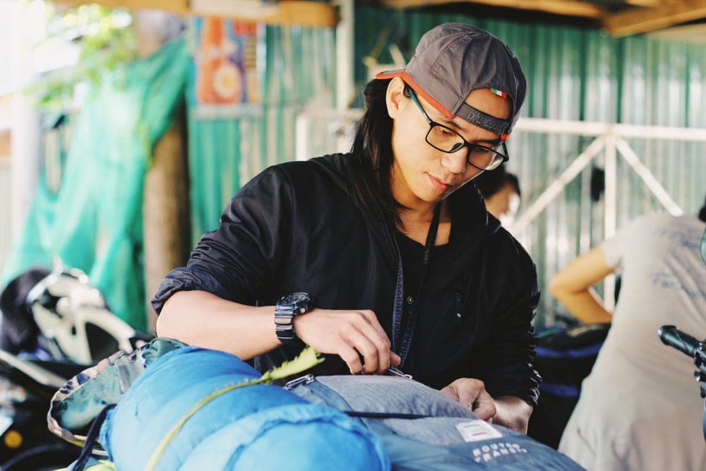 A man packing backpacks in a sunny backyard before a trip