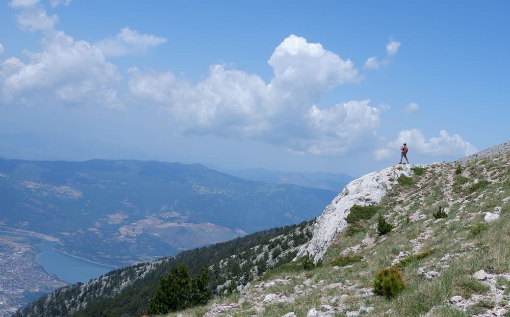 A hiker on a rocky ridge above a wide valley