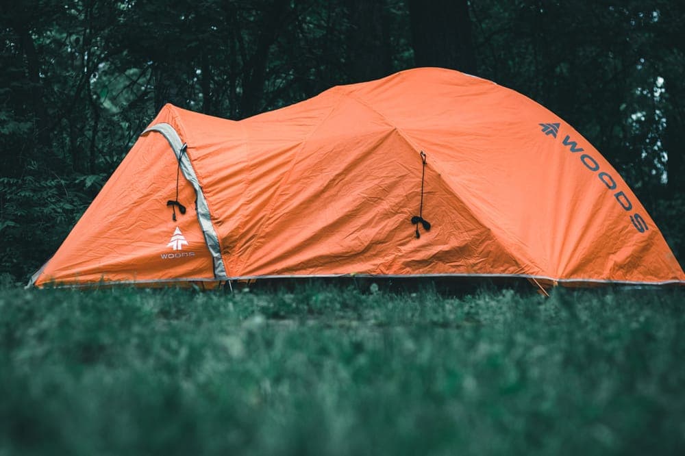 An orange tent pitched in a forest