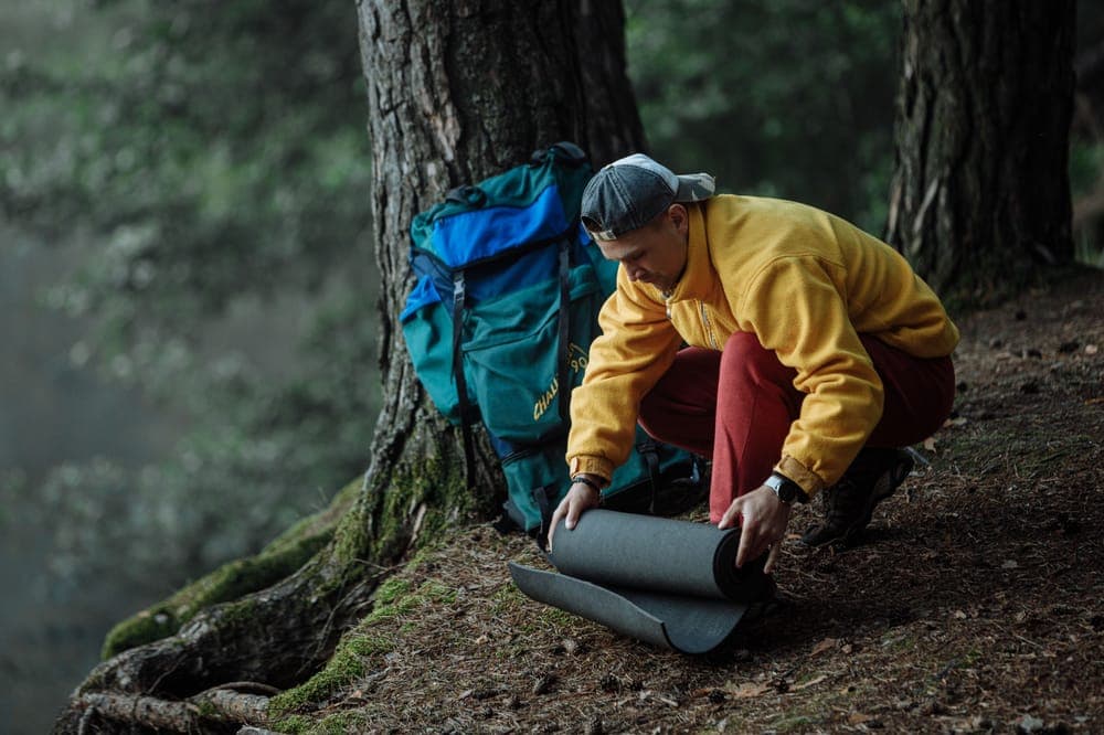 Illustrative stock photo: a camper setting up gear under trees
