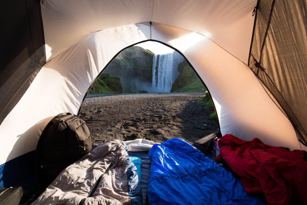 Illustrative stock photo: the view from inside a tent toward a waterfall