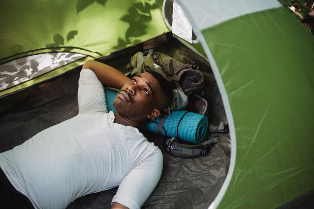 Illustrative stock photo: a hiker resting inside a tent, seen from above