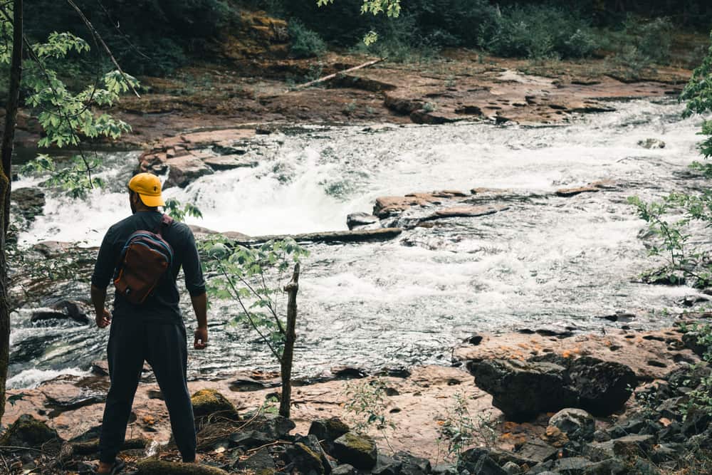 Illustrative stock photo: a hiker with a backpack beside a river