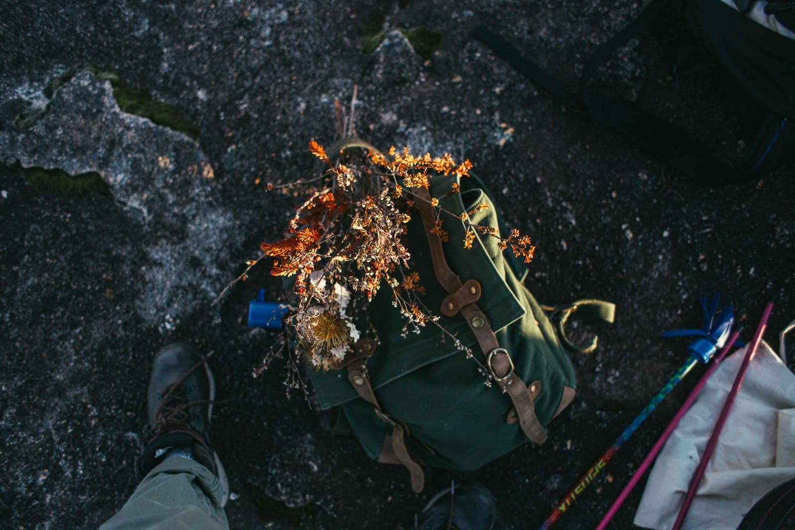 A backpacker standing beside a pack and trekking poles laid on the ground
